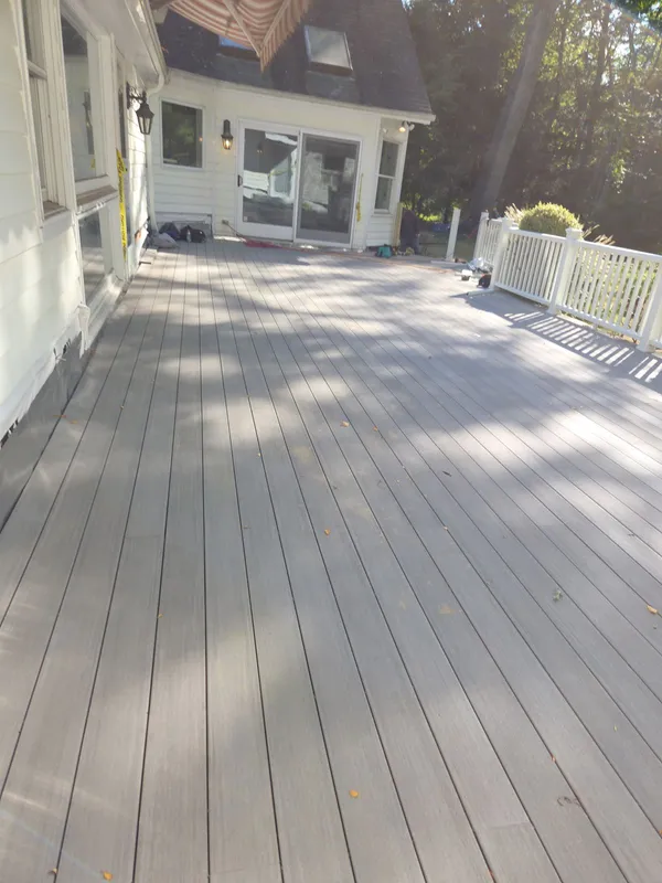 New gray composite deck with white railing behind a home.