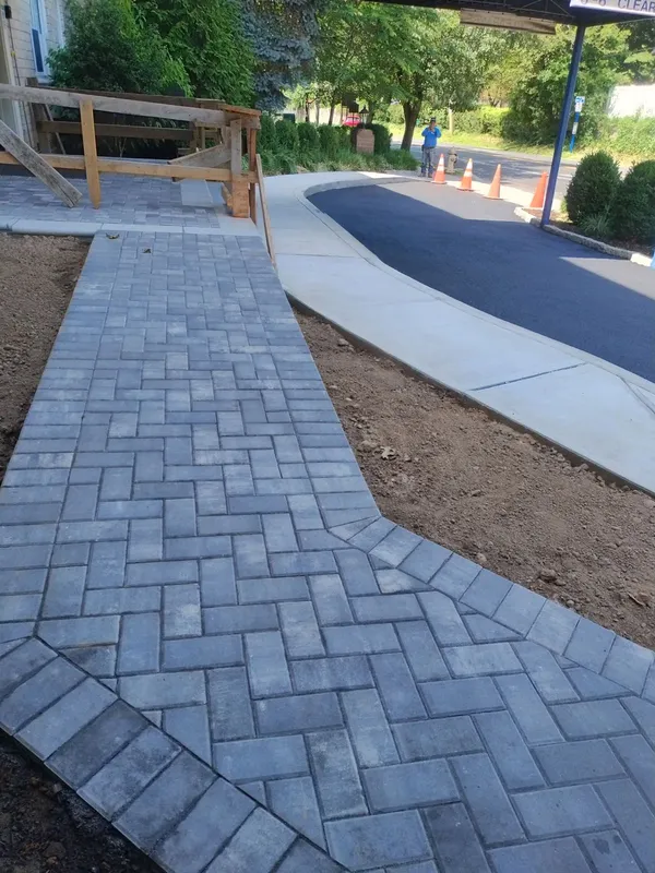 New gray paver walkway and driveway entrance with concrete curb.
