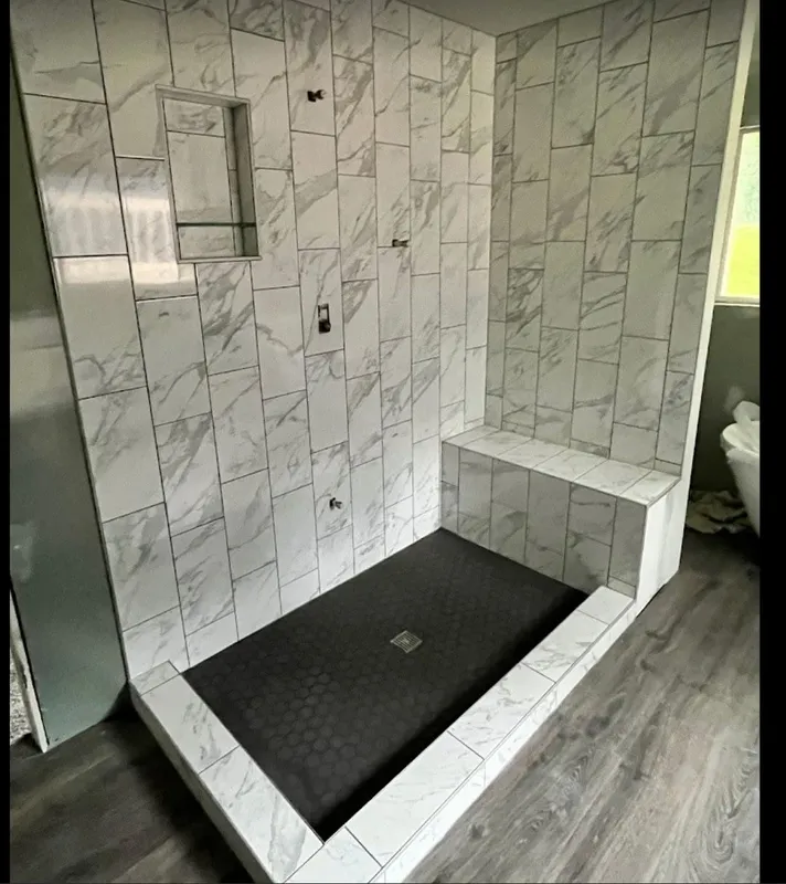 Marble walk-in shower with black hexagon floor and matte black fixtures.