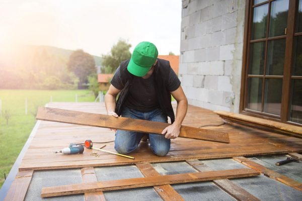 Handyman installing wooden flooring in patio outside the new house